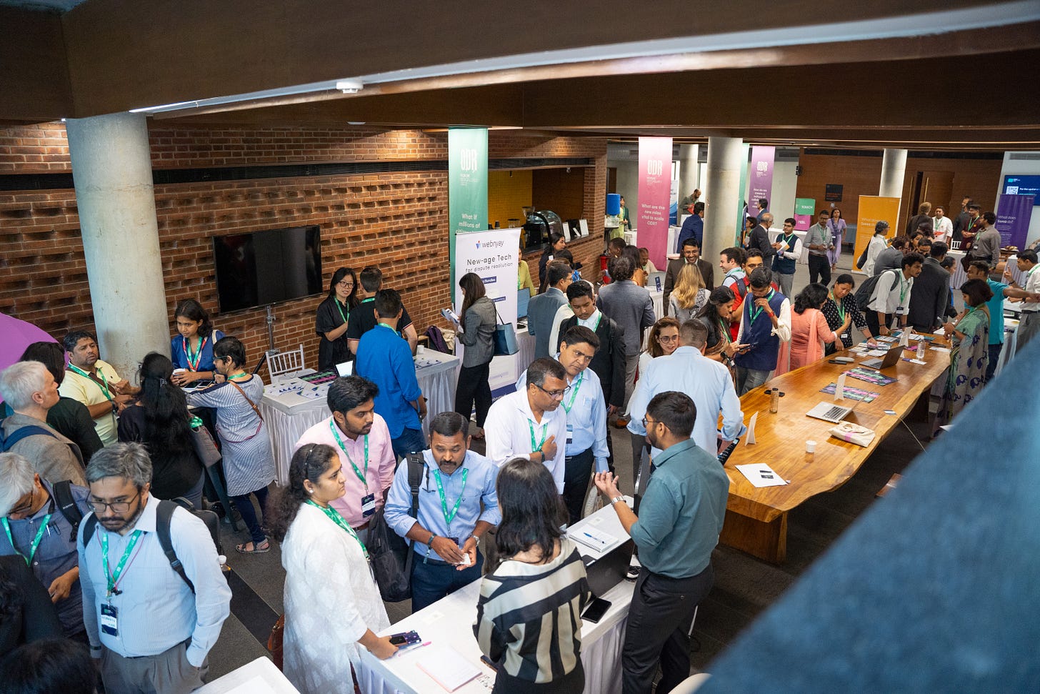 A crowd of people standing around different tables at a conference A crowd of people standing around different tables at a conference