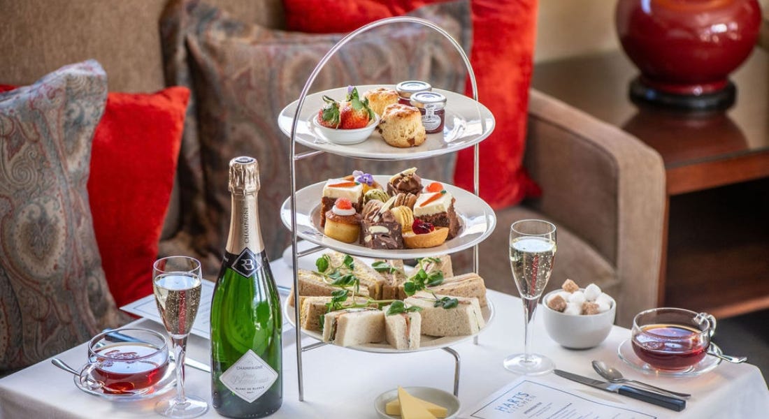 A tiered stand of afternoon tea with a bottle of champagne next to it