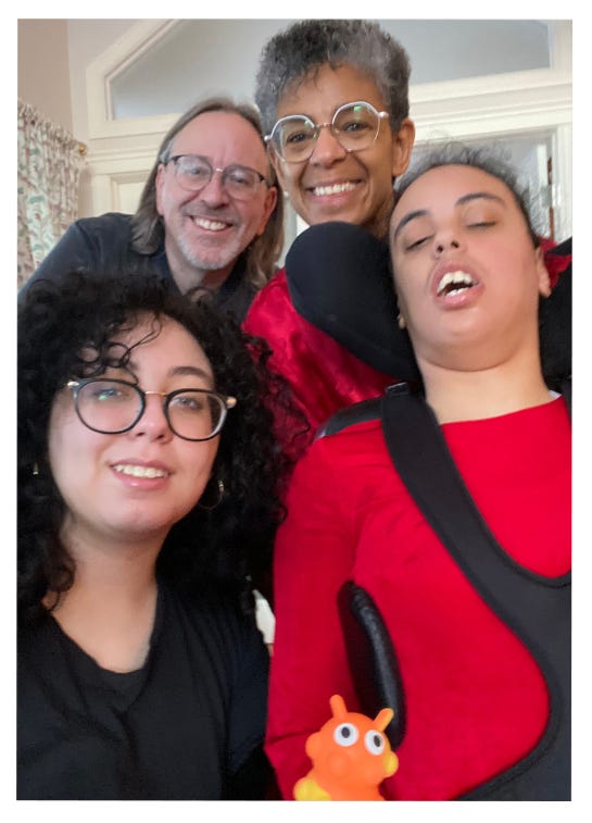 baby and young child together in a blue chair, Valeries's family smiling and wearing red and black.