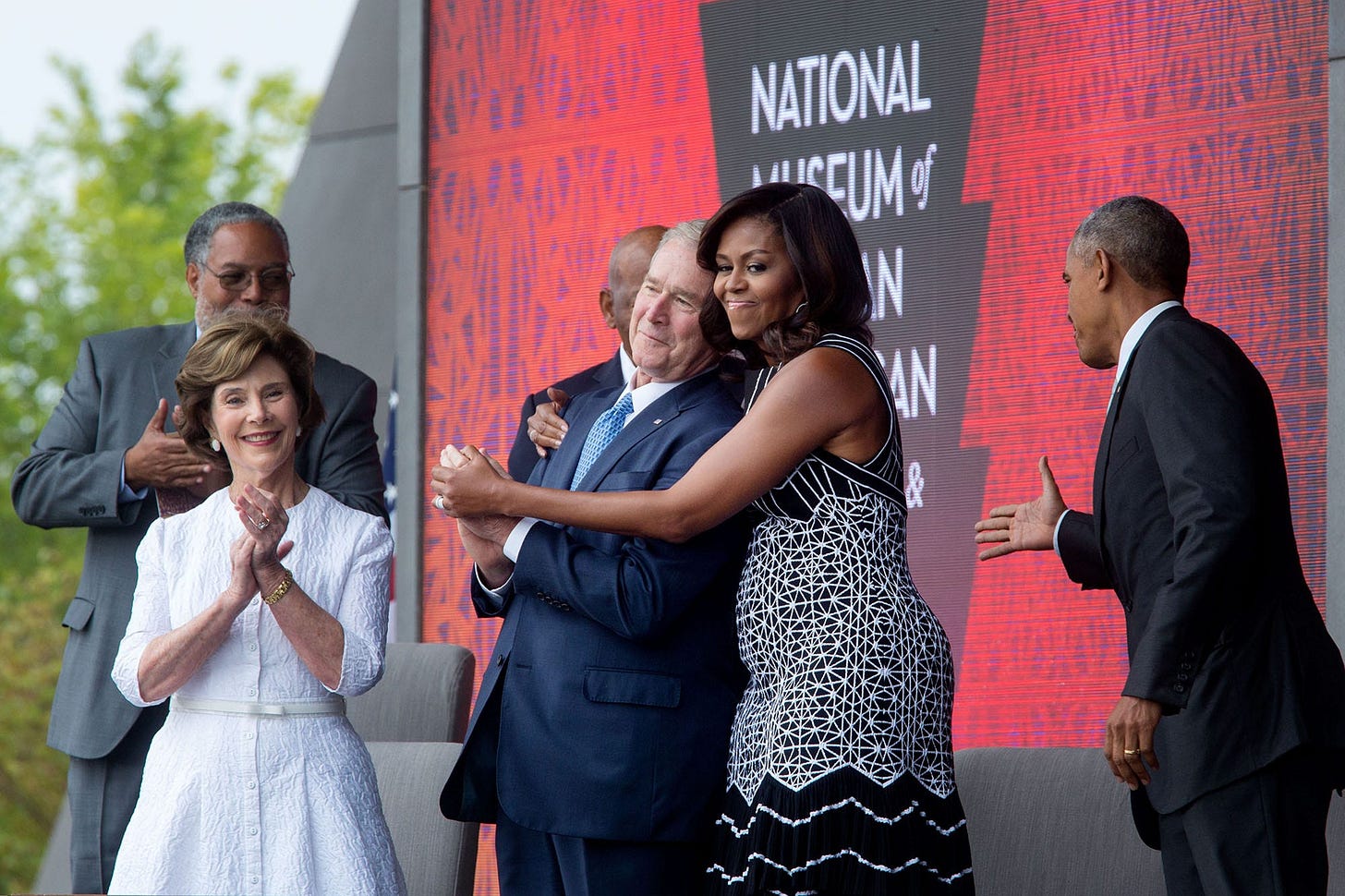 September 24, 2016: First Lady Michelle Obama shares a warm embrace with former President George W. Bush on stage at the opening ceremony of the Smithsonian National Museum of African American History and Culture. September 24, 2016: First Lady Michelle Obama shares a warm embrace with former President George W. Bush on stage at the opening ceremony of the Smithsonian National Museum of African American History and Culture.