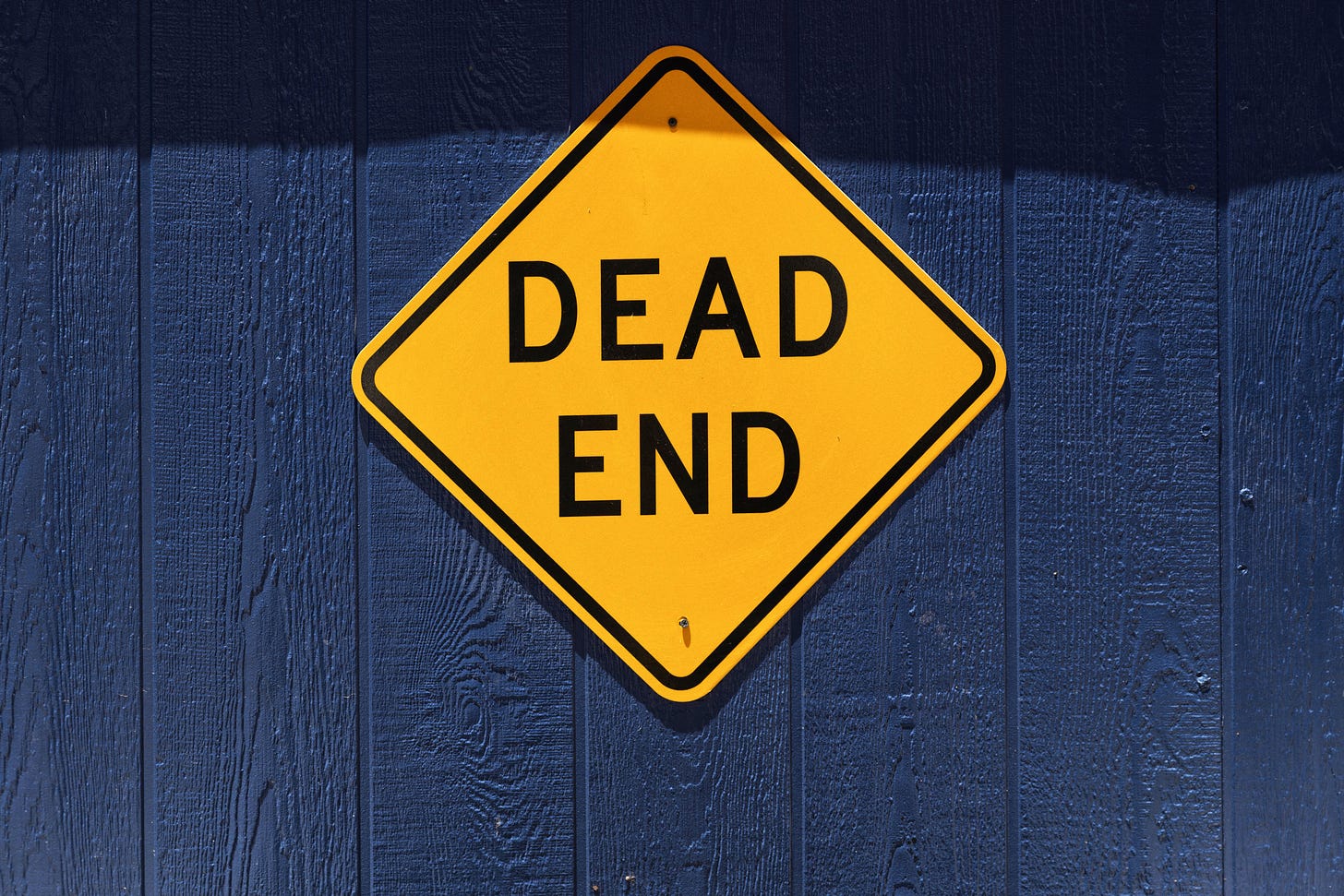 Cartello giallo a rombo con scritto "dead end" su sfondo blu