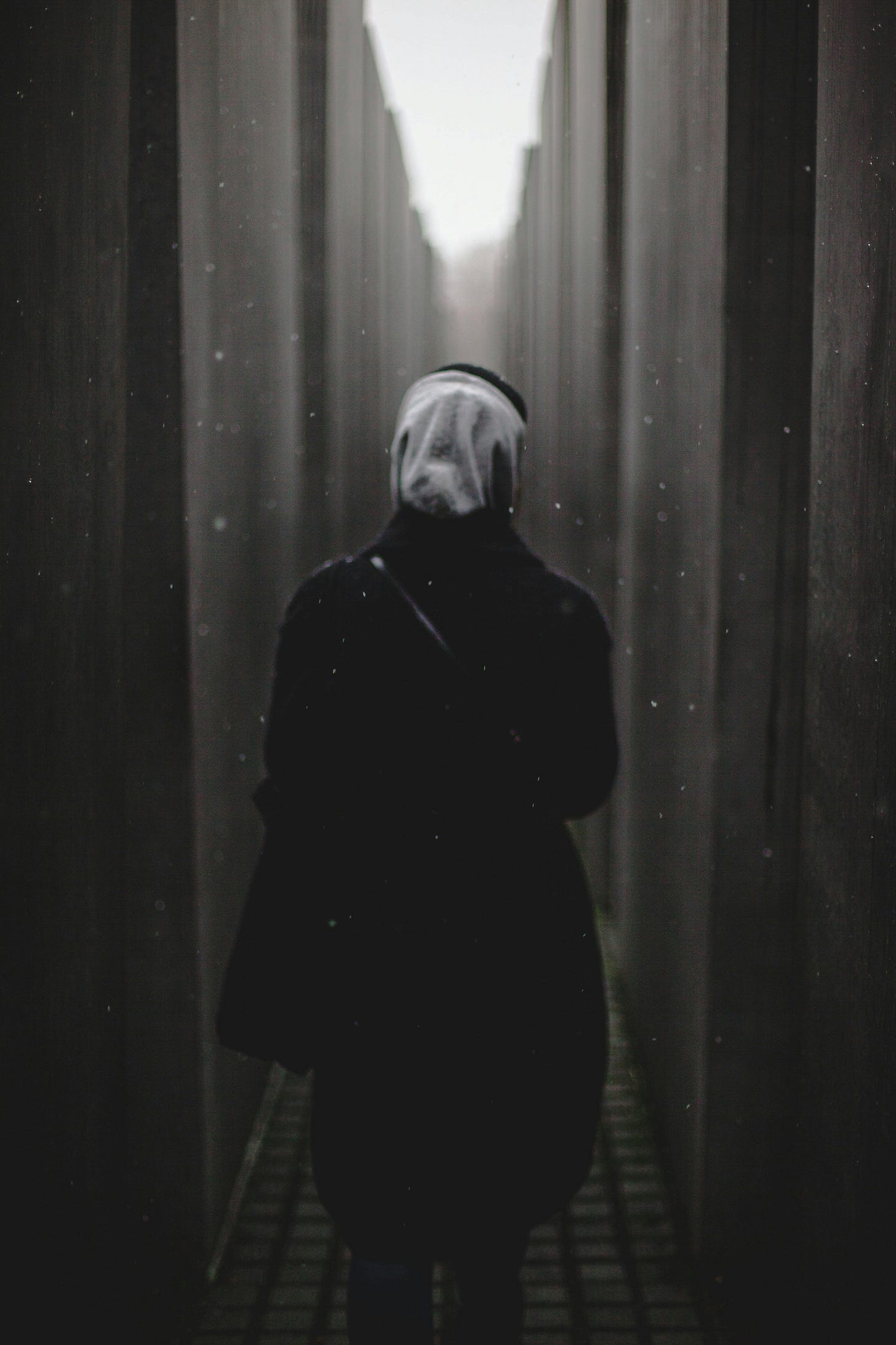 Black and white photo of a woman with a kerchief walking into a long narrow tunnel.