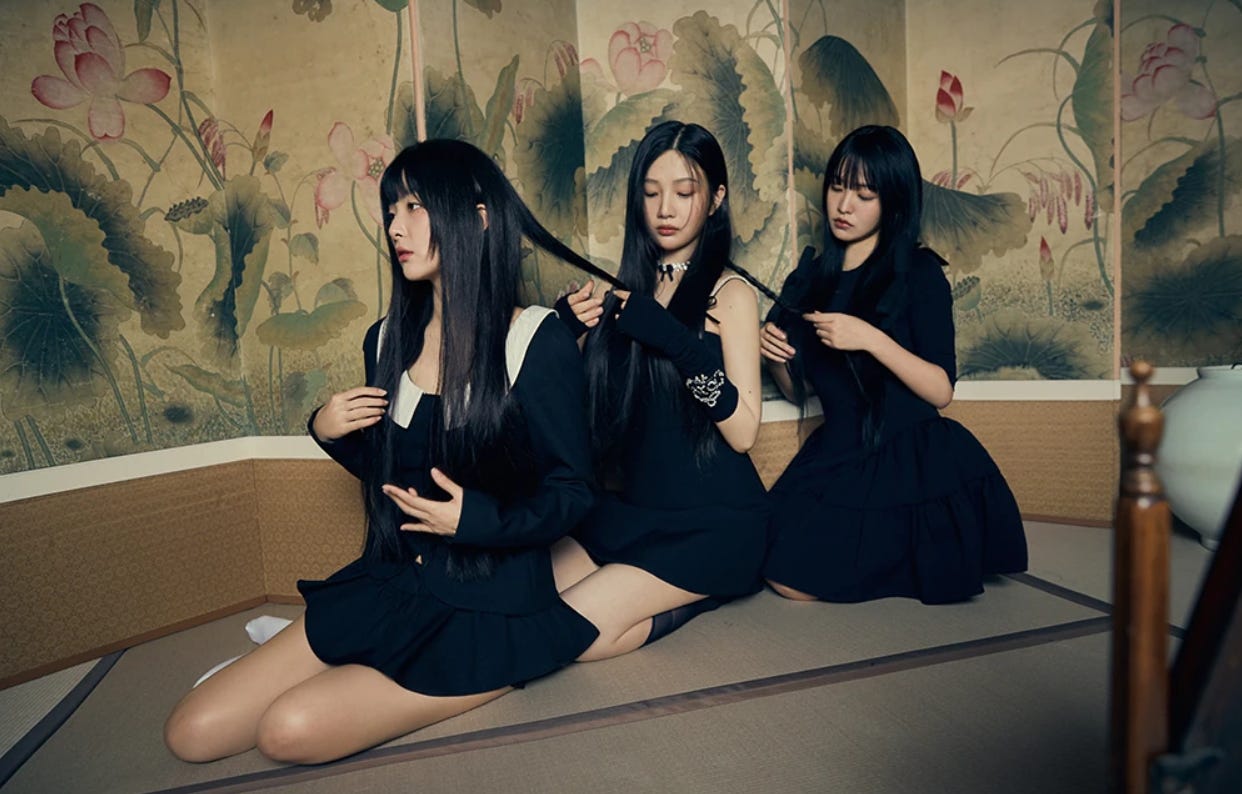 Red Velvet members Seulgi, Joy, and Yeri dressed in black framed for a portrait.
