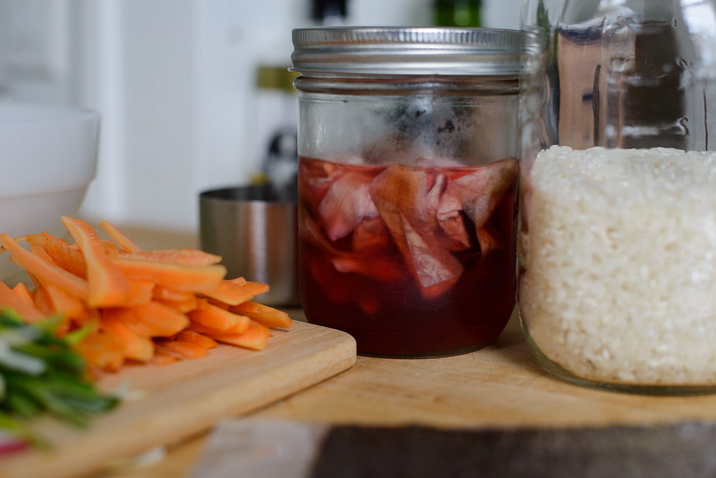 Magnolia pickles in a jar sitting on the counter with other ingredients.