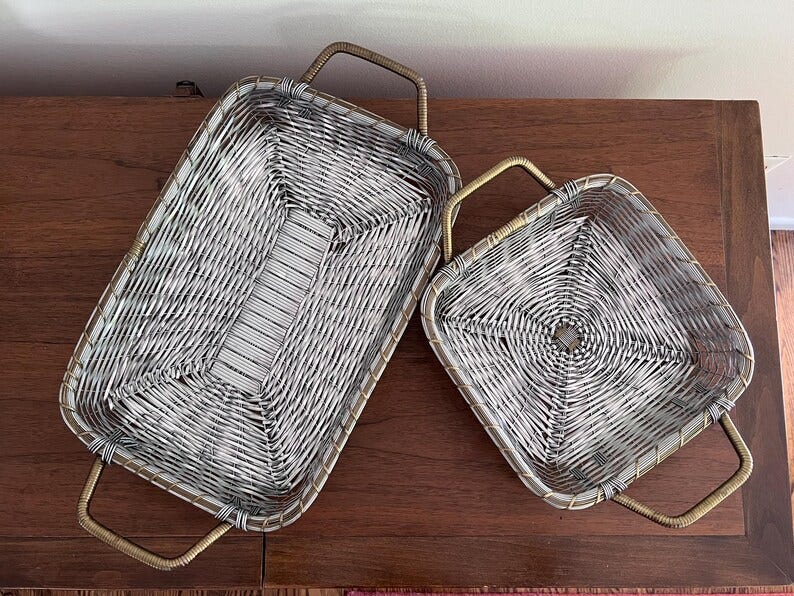 May include: Two silver wire baskets with gold handles. The larger basket is rectangular and the smaller basket is square.