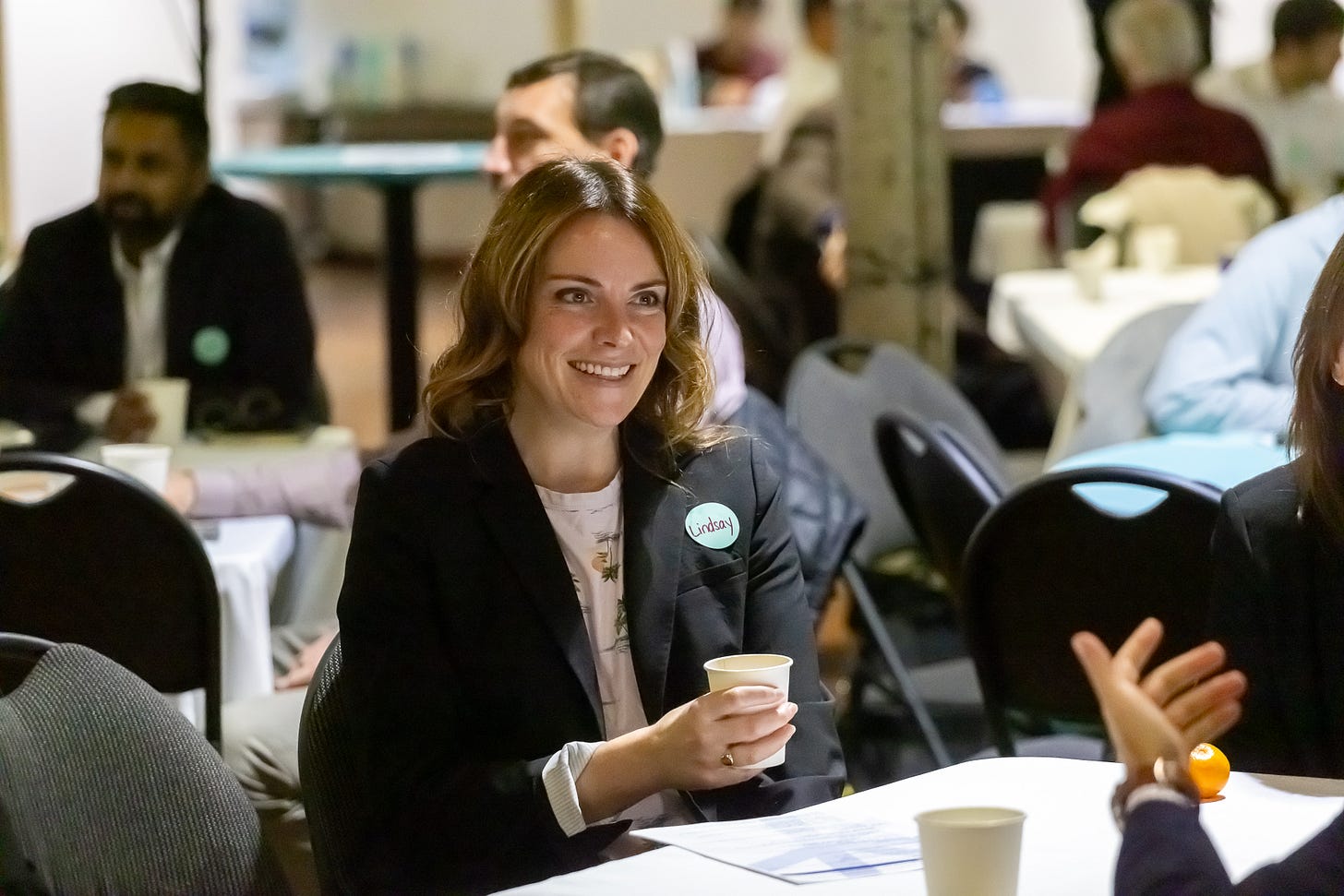 Linsday Hampson at a business event, holding a coffee cup Linsday Hampson at a business event, holding a coffee cup