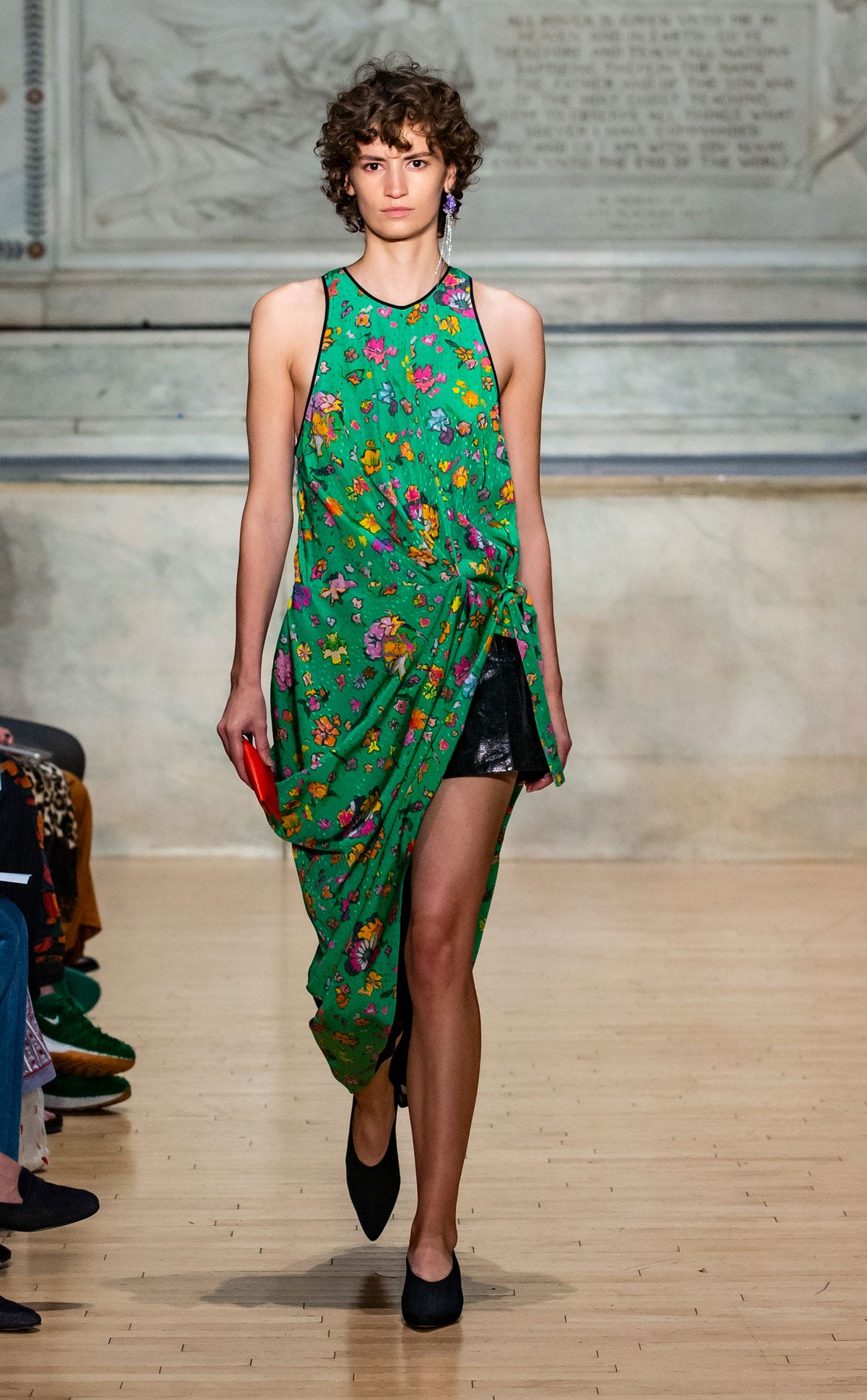 A model in a sleeveless green floral dress with a draped asymmetric skirt over black shorts on the Rachel Comey runway