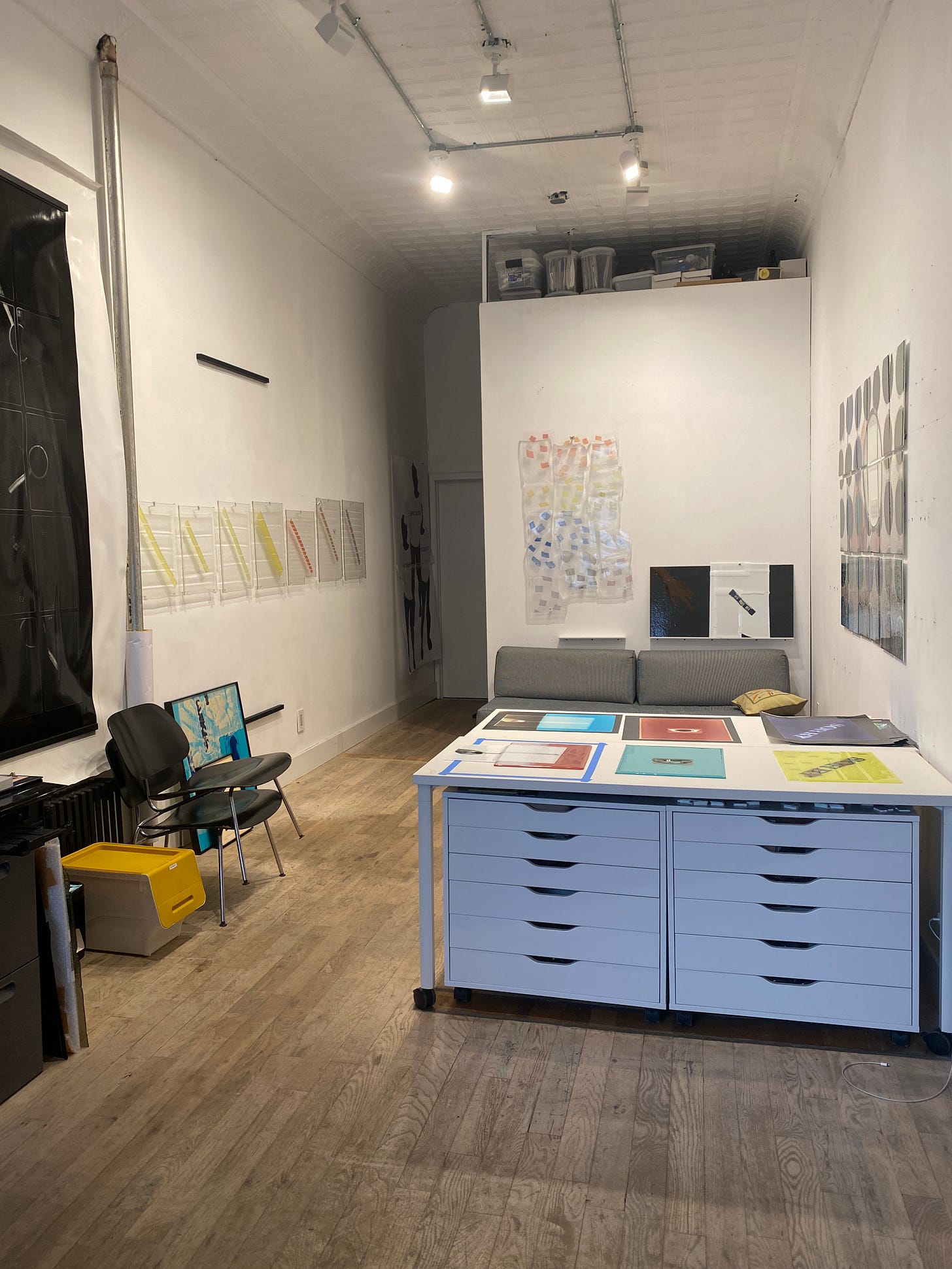an image of Sara's studio with studio lighting, white walls, wood floors, and art on the walls and tables