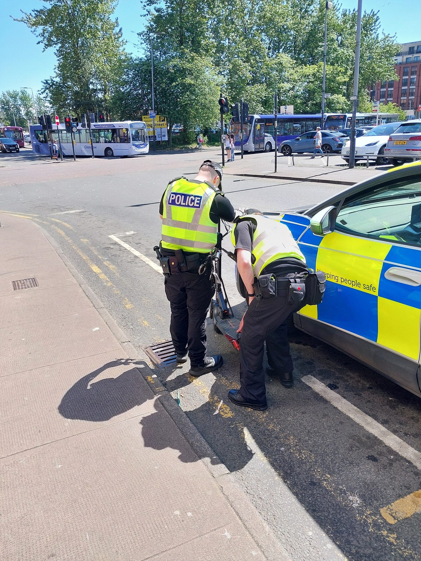 Two police officers are carrying out checks on an E-scooter as part of a road safety day of action in Greater Glasgow Division.
