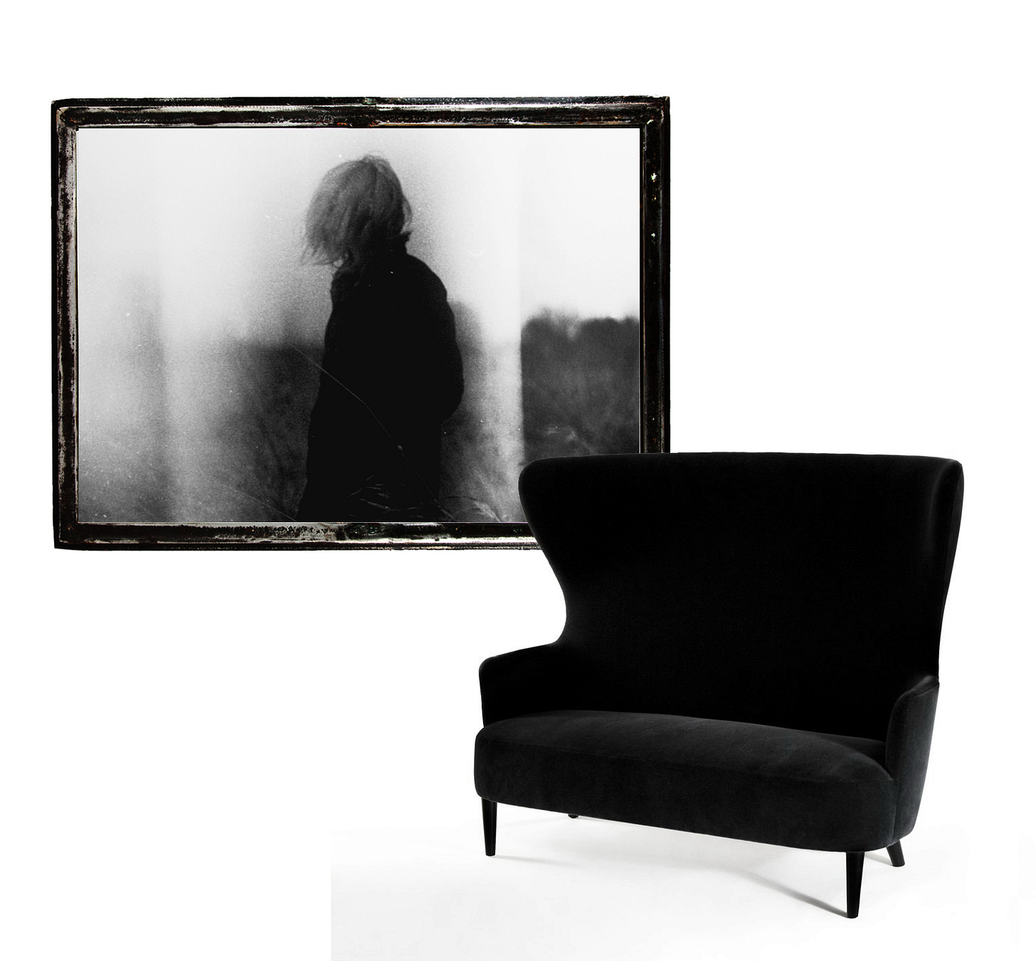 a black armchair, behind which a framed image of a woman turning away from the viewer