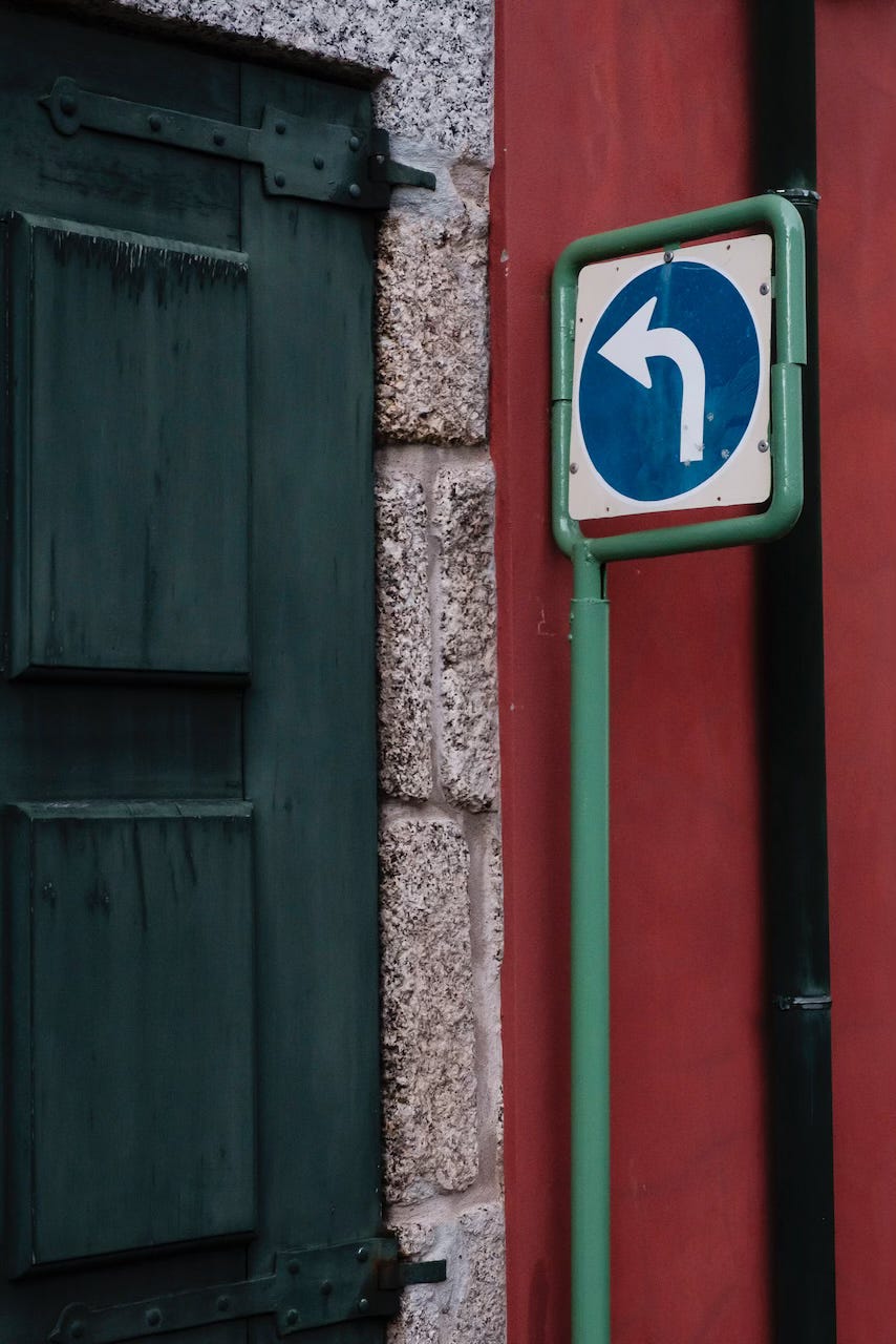 A turn left sign against a red wall in the streets of central Guimarães, Portugal