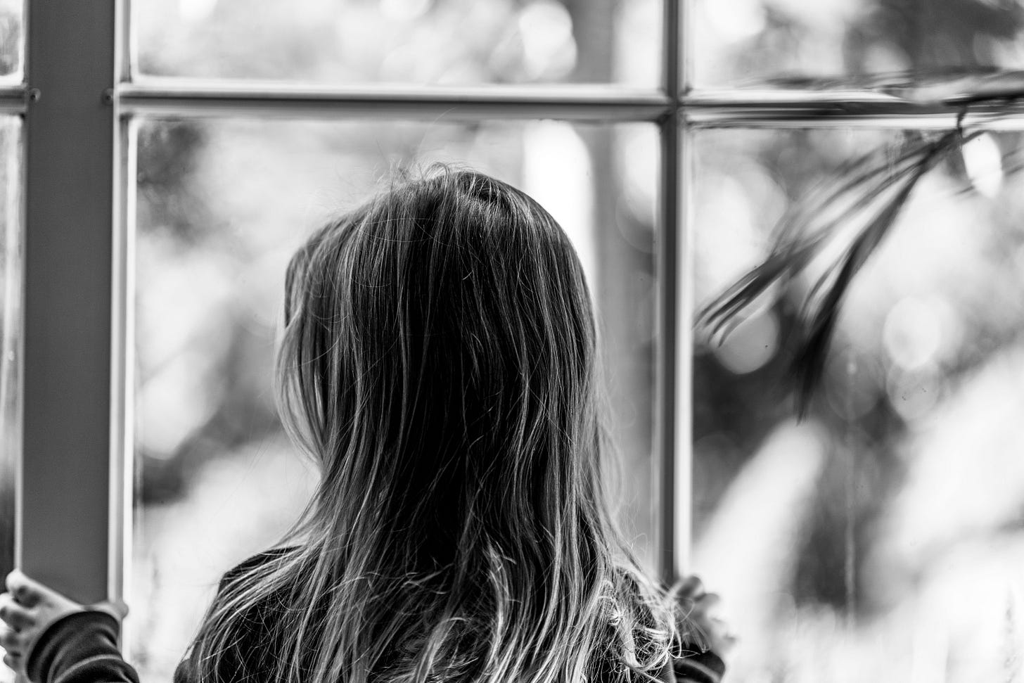 Young girl at window, back to camera