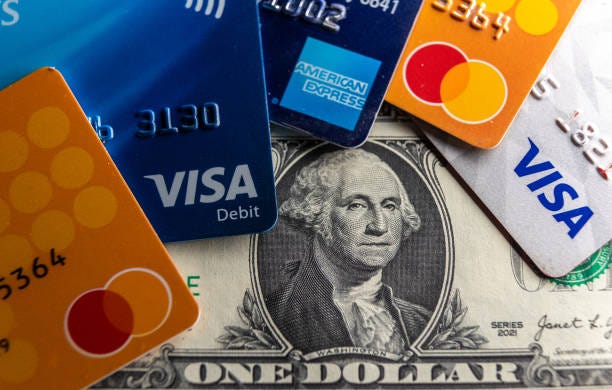 In this photo illustration the Visa, Mastercard and American Express logo on various credit cards and debit cards are seen beside US one dollar bills...