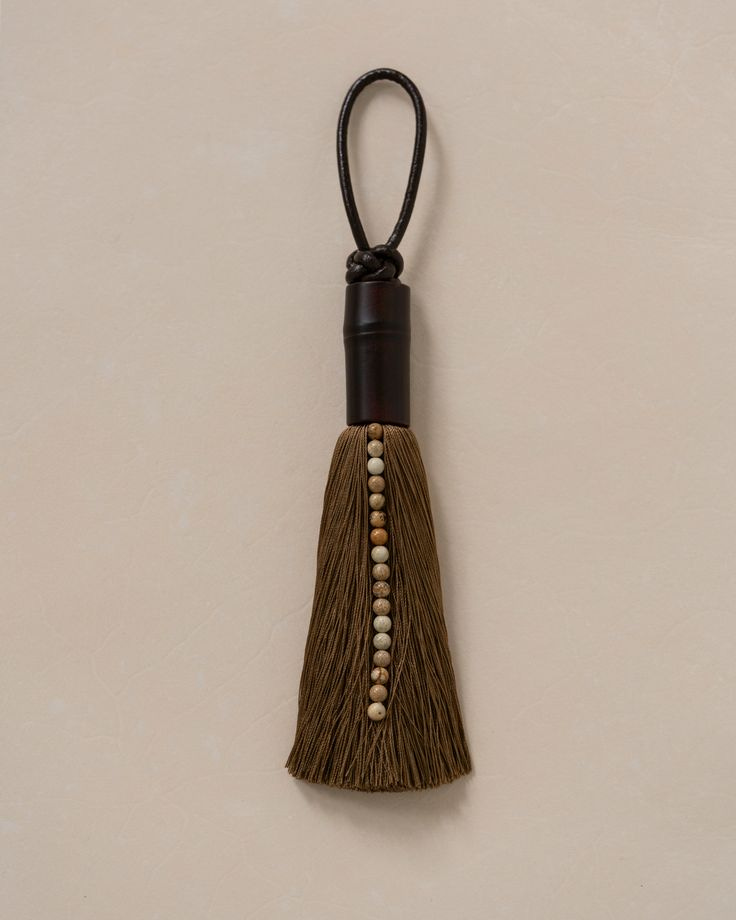 This may contain: a tassel hanging on the wall with beads and wood beads attached to it's end