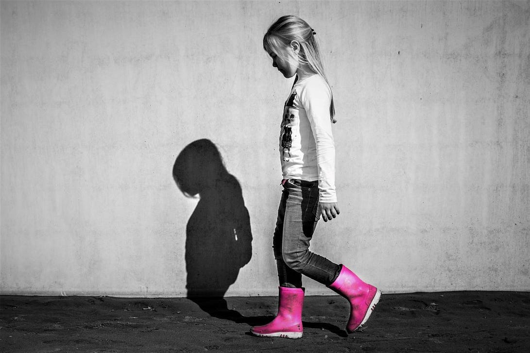 A small girl with pink wellies, her shadow is visible