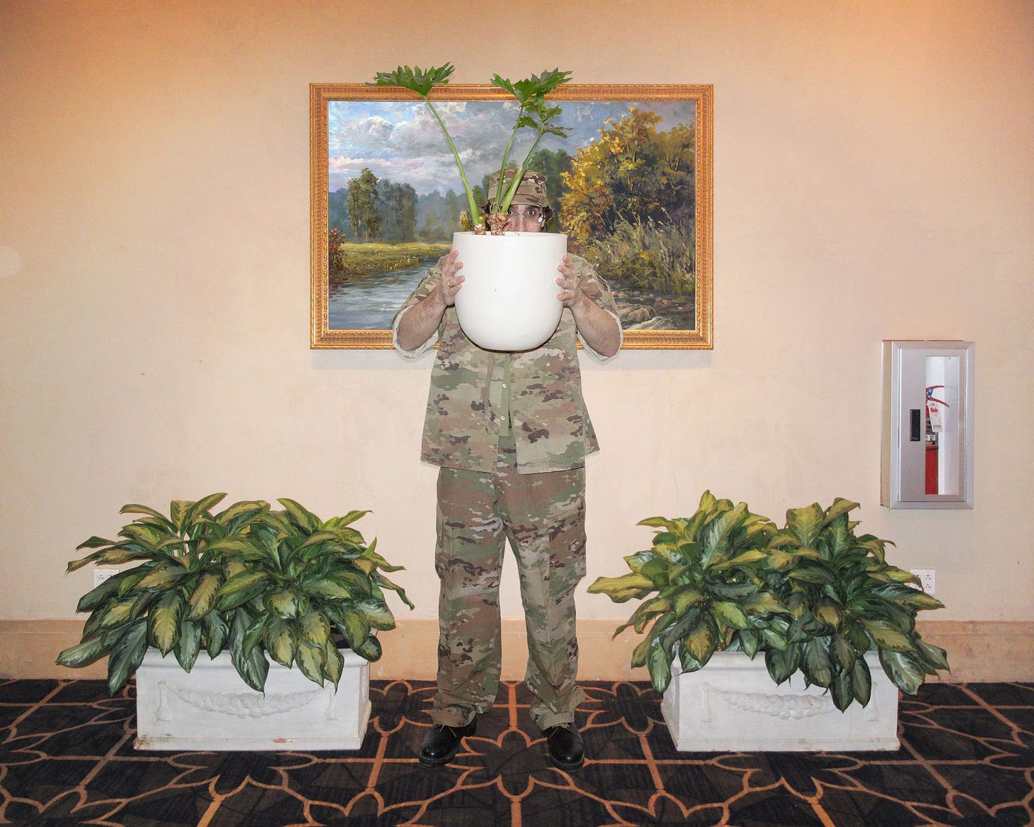 Person hiding behind a planter wearing camouflage clothing Person hiding behind a planter wearing camouflage clothing