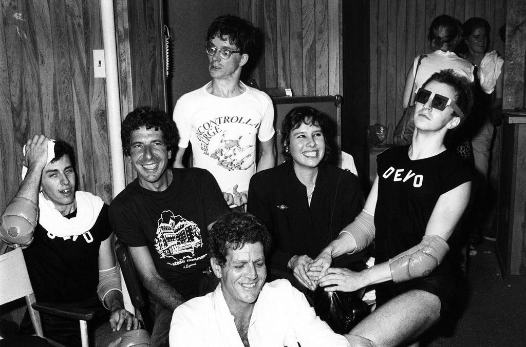 Leonard Cohen, David Blue, Mark Mothersbaugh of Devo, Martine Getty and a Devo member backstage at The Starwood in Los Angeles in 1970. Leonard Cohen, David Blue, Mark Mothersbaugh of Devo, Martine Getty and a Devo member backstage at The Starwood in Los Angeles in 1970.