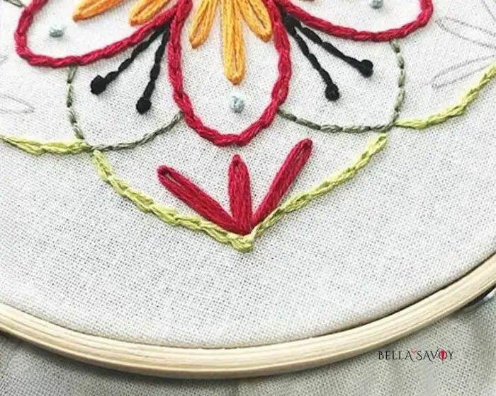 three red lazy daisy stitches at the tip of the manadala embroidery