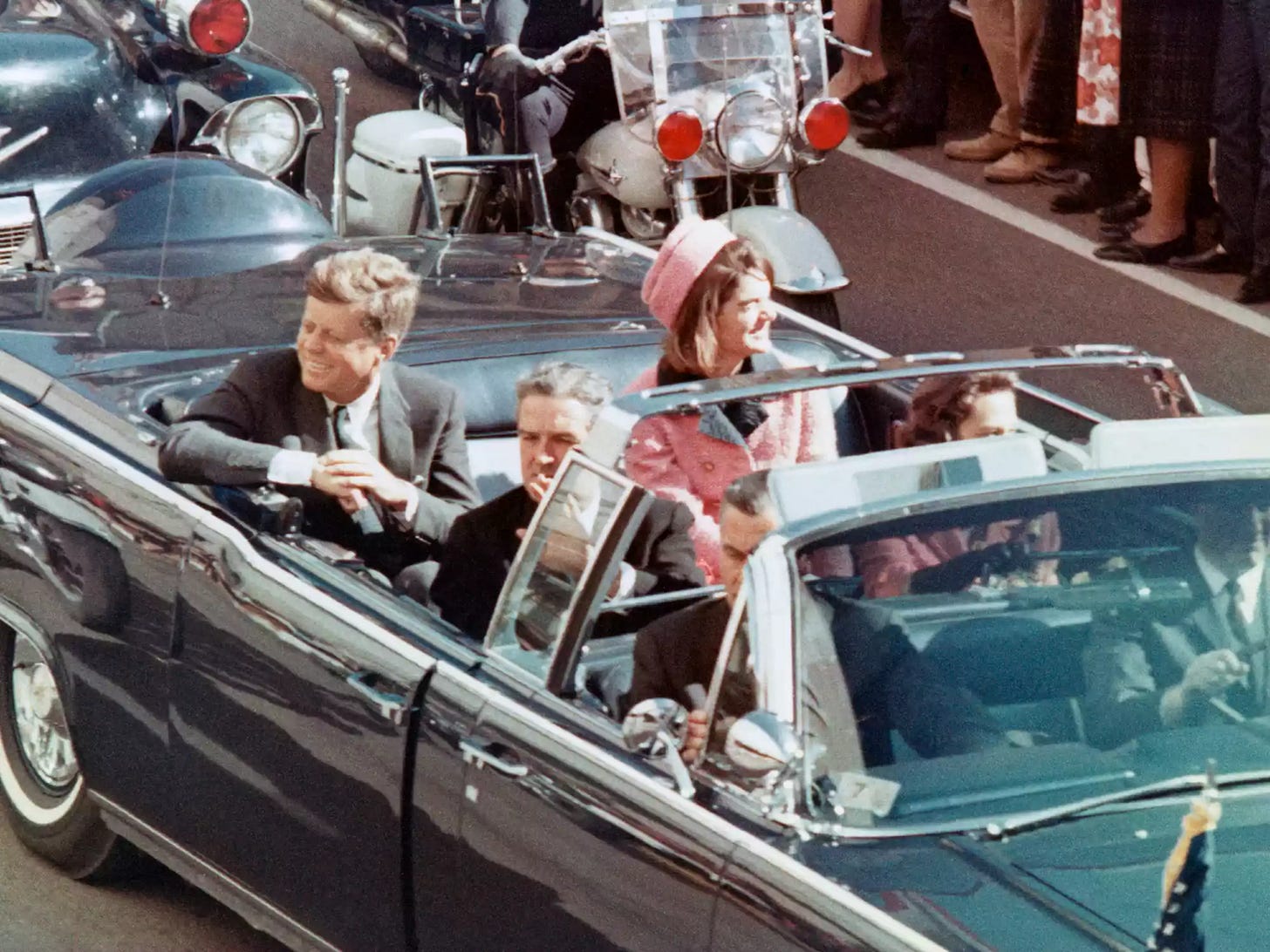 US President John F Kennedy, First Lady Jacqueline Kennedy, Texas Governor John Connally, and others smile at the crowds lining their motorcade route in Dallas, Texas, on November 22, 1963. Credit: Bettmann.