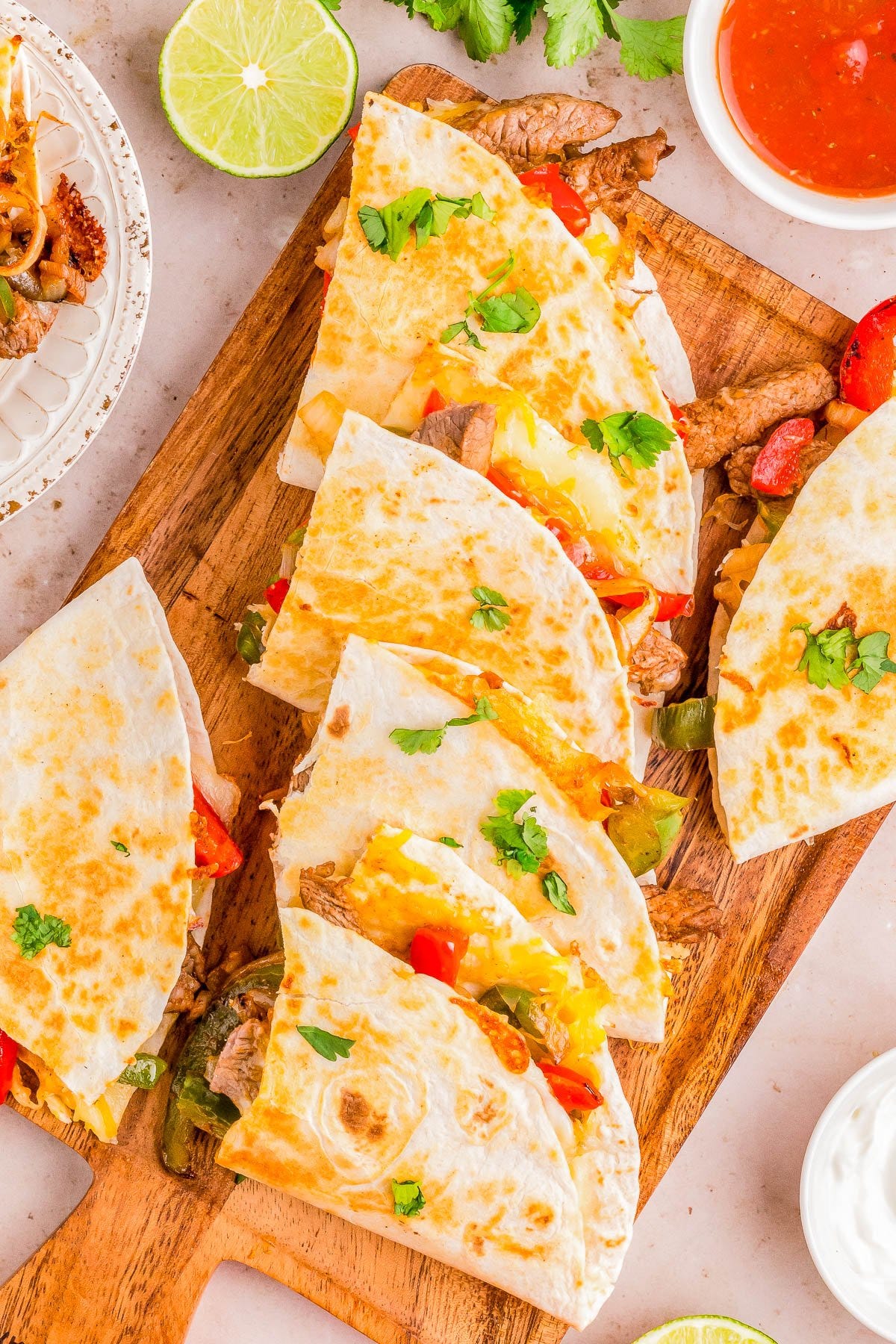 Platter of steak quesadillas garnished with peppers, tomatoes, and cilantro. 
