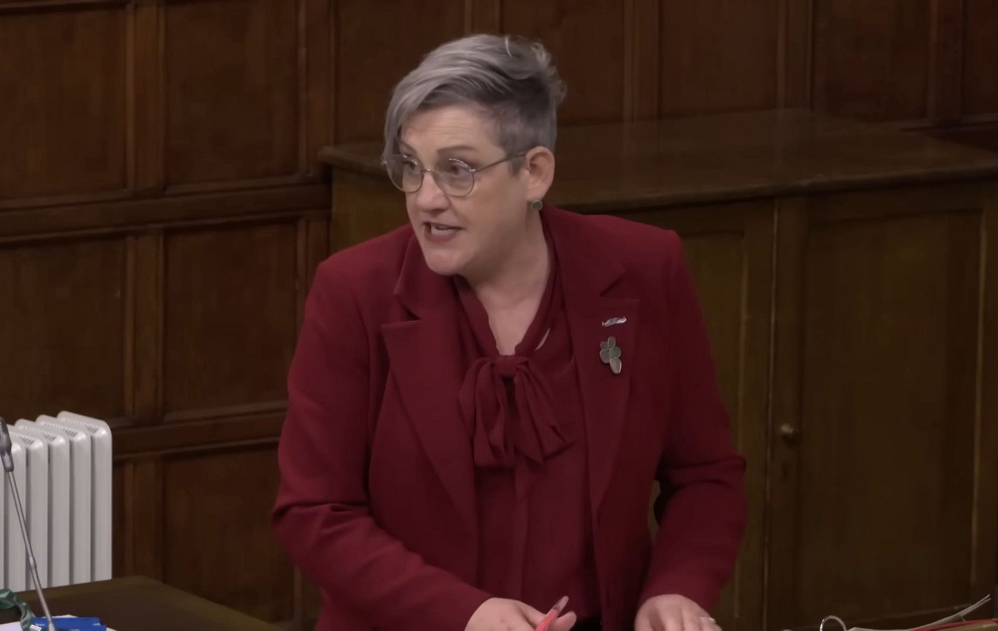 Ashley Dalton, wearing burgundy, speaking at the debate. A radiator can be seen in the background.
