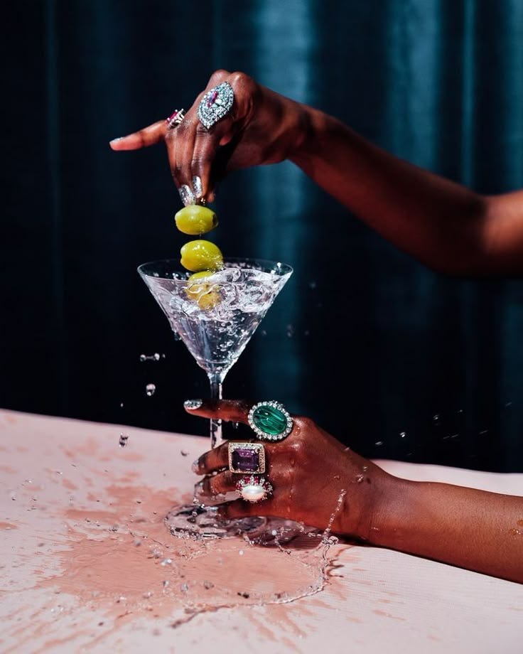 This may contain: two hands are reaching into a martini glass filled with limes and lemonade slices