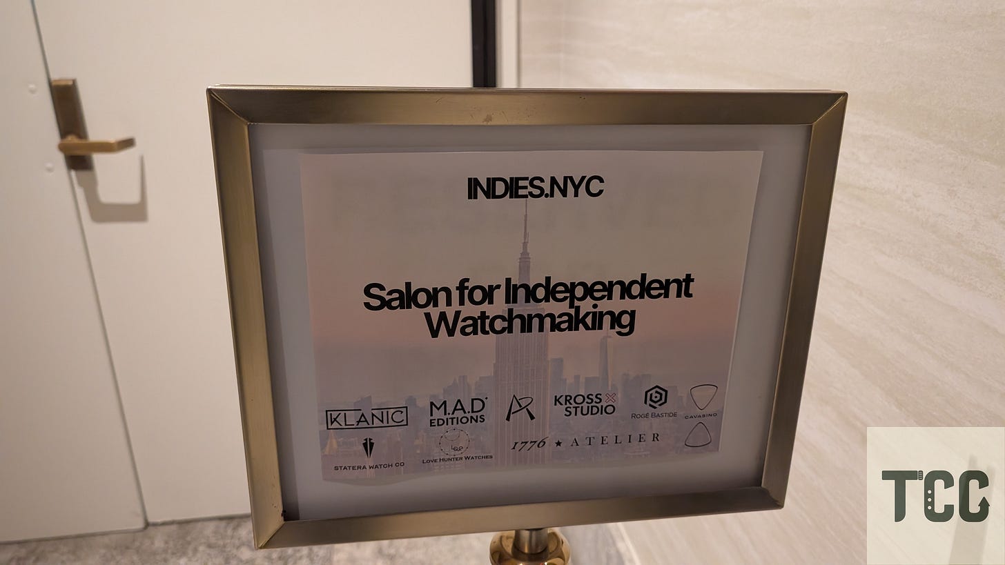 A sign reading “Salon for Independent Watchmaking” with logos of participating brands including Klanic, MAD Editions, Kross Studio, Rogé Bastide, 1776 Atelier, and others. The Empire State Building is subtly visible in the background of the sign’s design.