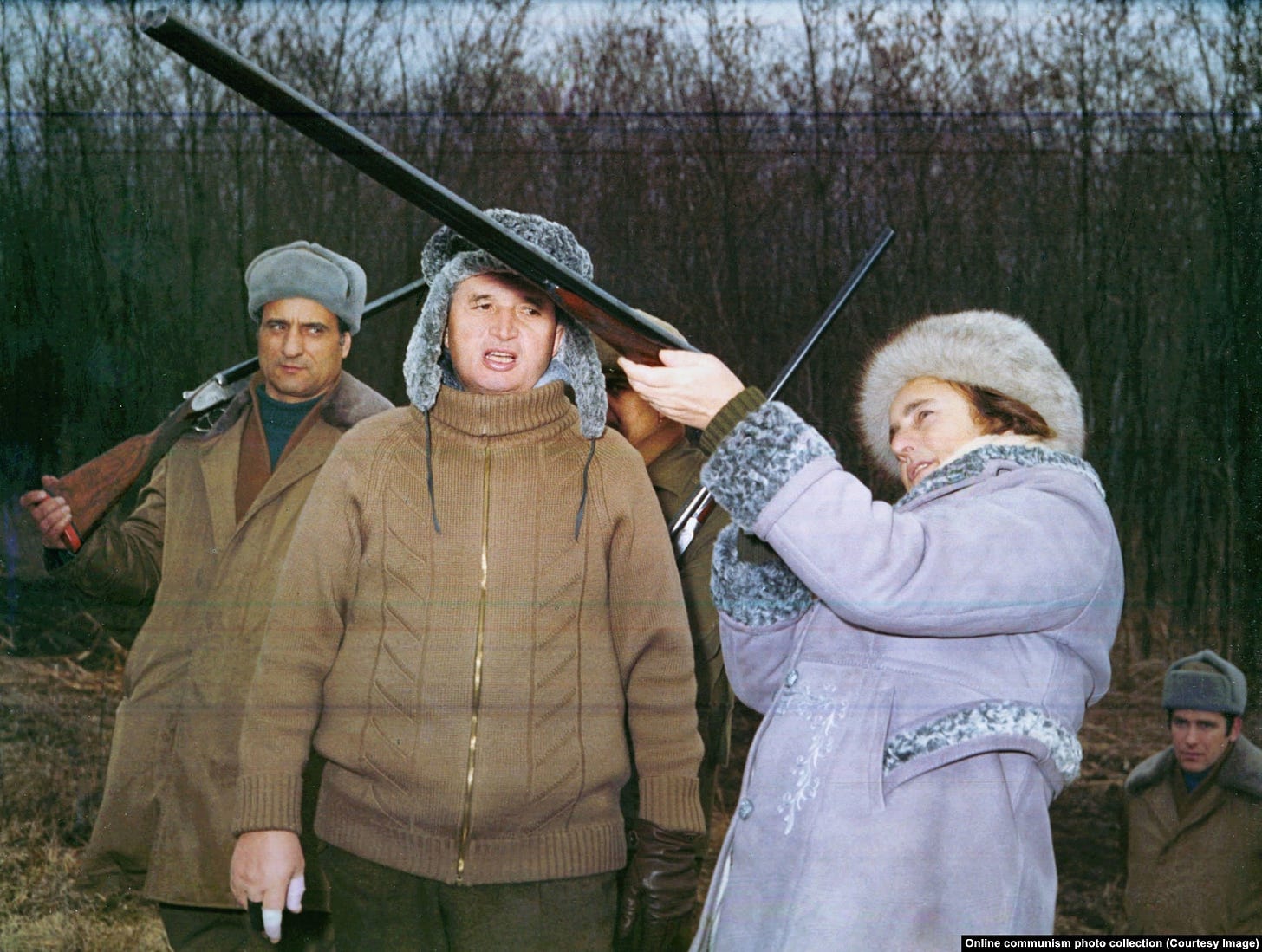 Nicolae Ceausescu, sporting a bandaged trigger finger, watches his wife, Elena, take aim with a shotgun during a New Year’s Eve hunting trip in 1976.