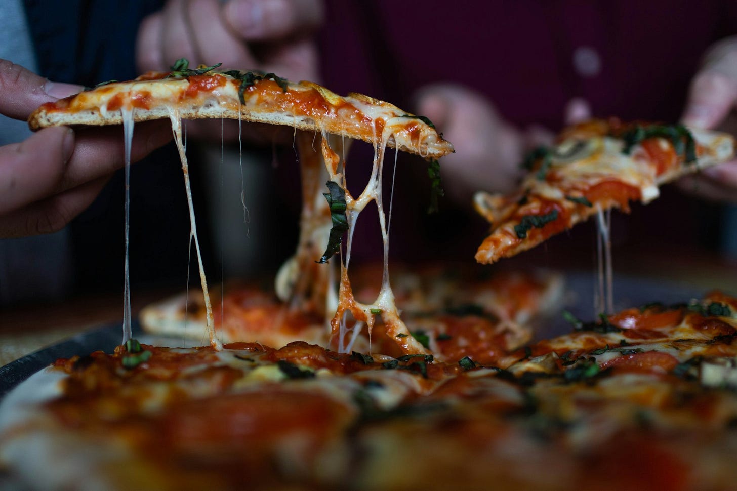 person picking up sliced pizza