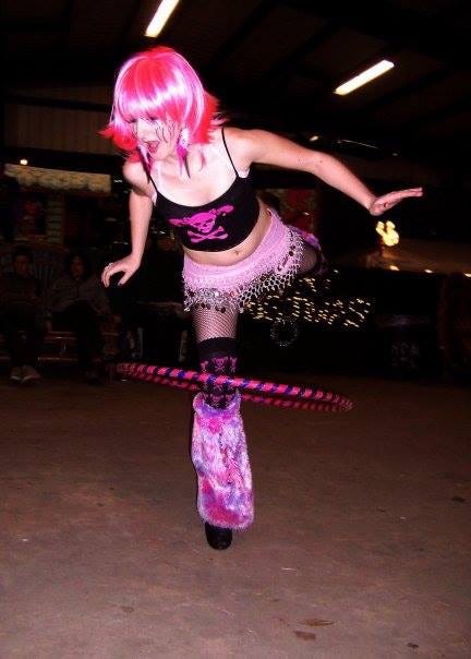 20-something Lyric, in a hot pink wig and patching hot pink outfit, hooping with a pink and purple hoop on their knee at one of the indoor Electro Circus events. 20-something Lyric, in a hot pink wig and patching hot pink outfit, hooping with a pink and purple hoop on their knee at one of the indoor Electro Circus events.