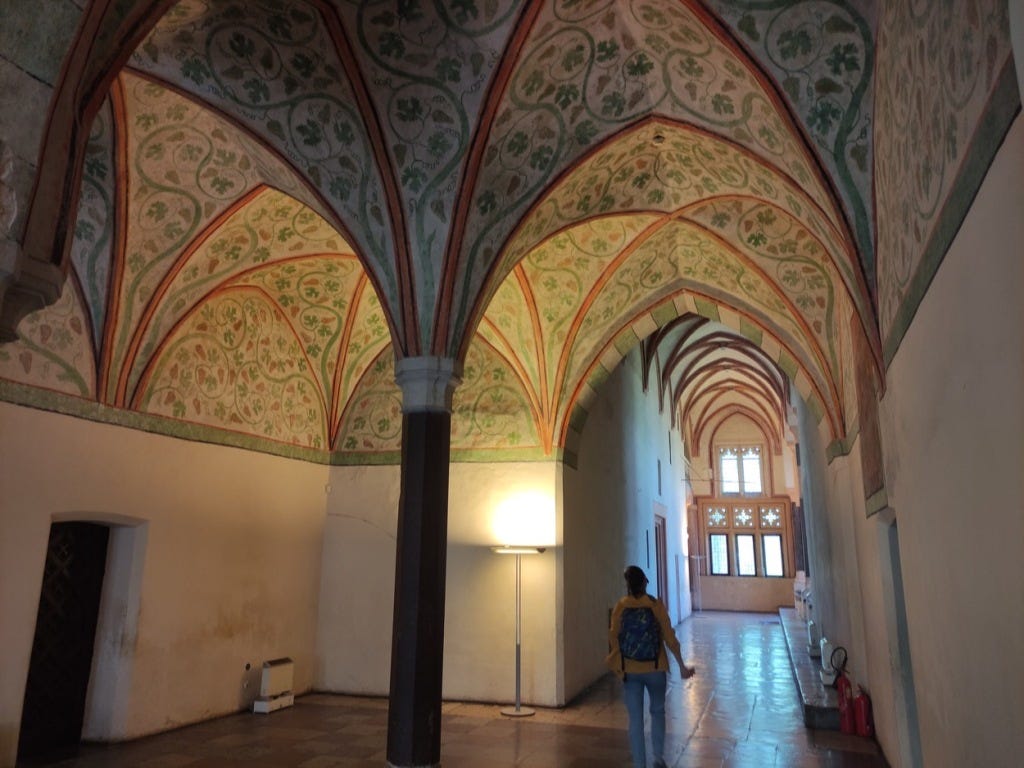 More curved arches in the roof of a corridor, painted with creepers and flowers.