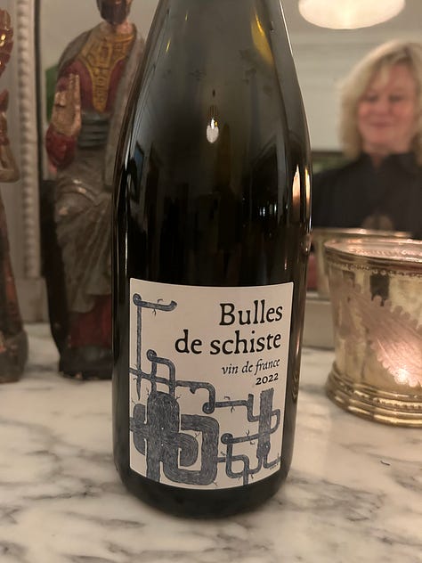 bottles of French wine from two tastings. Wines of Burgundy and the Loire Valley. Plates of appetizers on a wooden table.