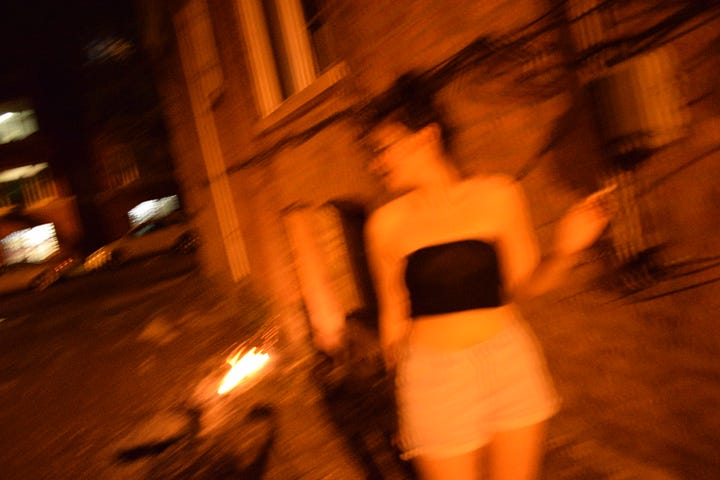 four photos of a young woman standing or crouching before burning poplar fluff in an alley