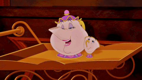 Gif del film d'animazione Disney La Bella e la Bestia. I personaggi Mrs. Bric (una teiera di porcellana) e Chicco (una tazza di porcellana) sono ritratti su un carrello da portata color oro. Mrs. Bric ha un'espressione gentile e sorridente, mentre Chicco, al suo fianco, la guarda con affetto. Entrambi i personaggi sono decorati con tonalità di bianco, rosa e viola. La scena ha uno sfondo scuro e si svolge all'interno di un palazzo.