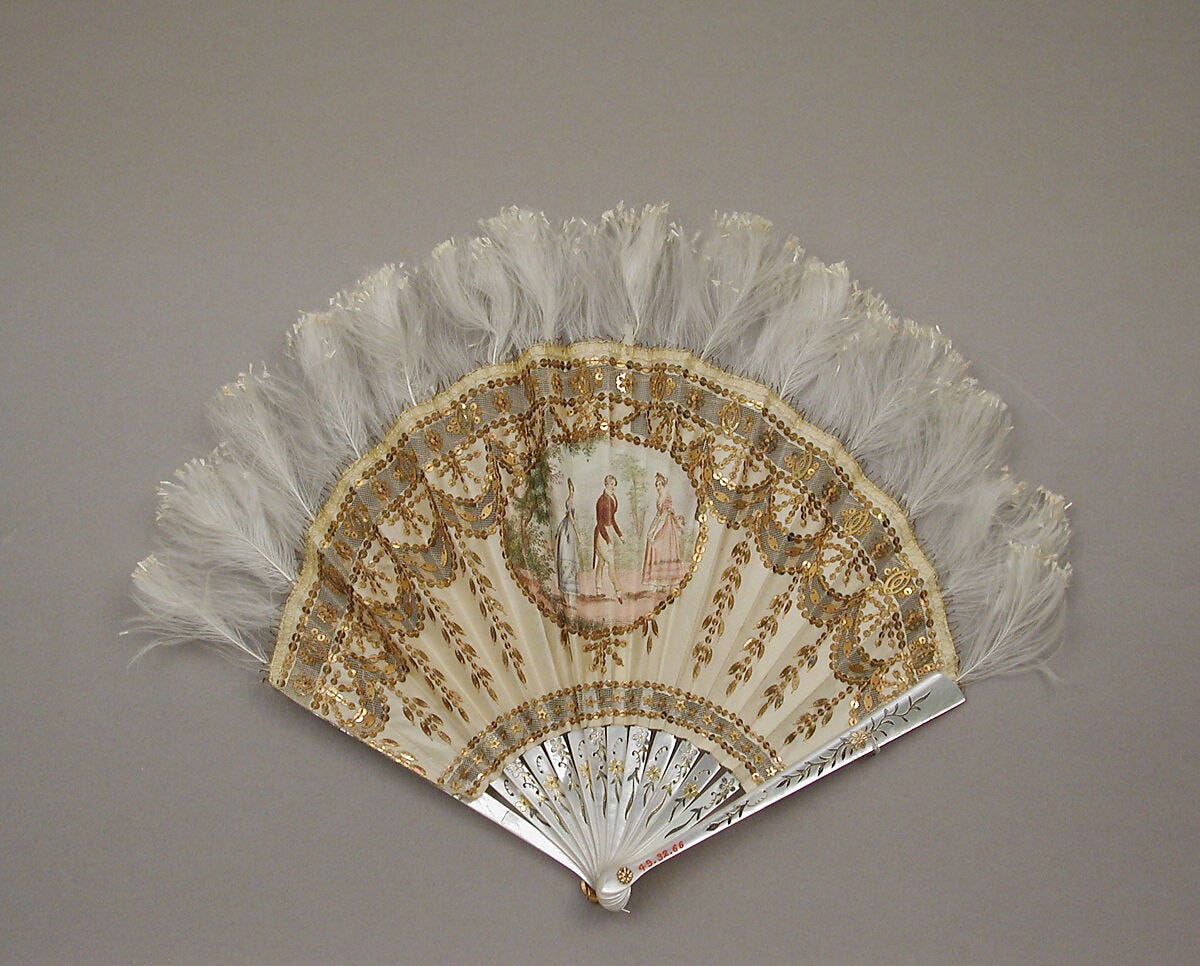 an off-white fan trimmed with features featuring a picture of three figures in the center