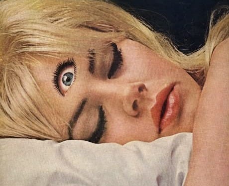 This may contain: a woman laying on top of a bed with her eyes closed and hands behind her head