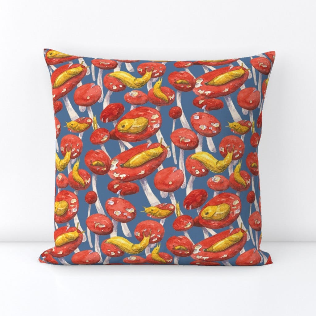 Spoonflower.com image of a throw pillow using fabric with banana slugs on red mushroom caps over a blue background.