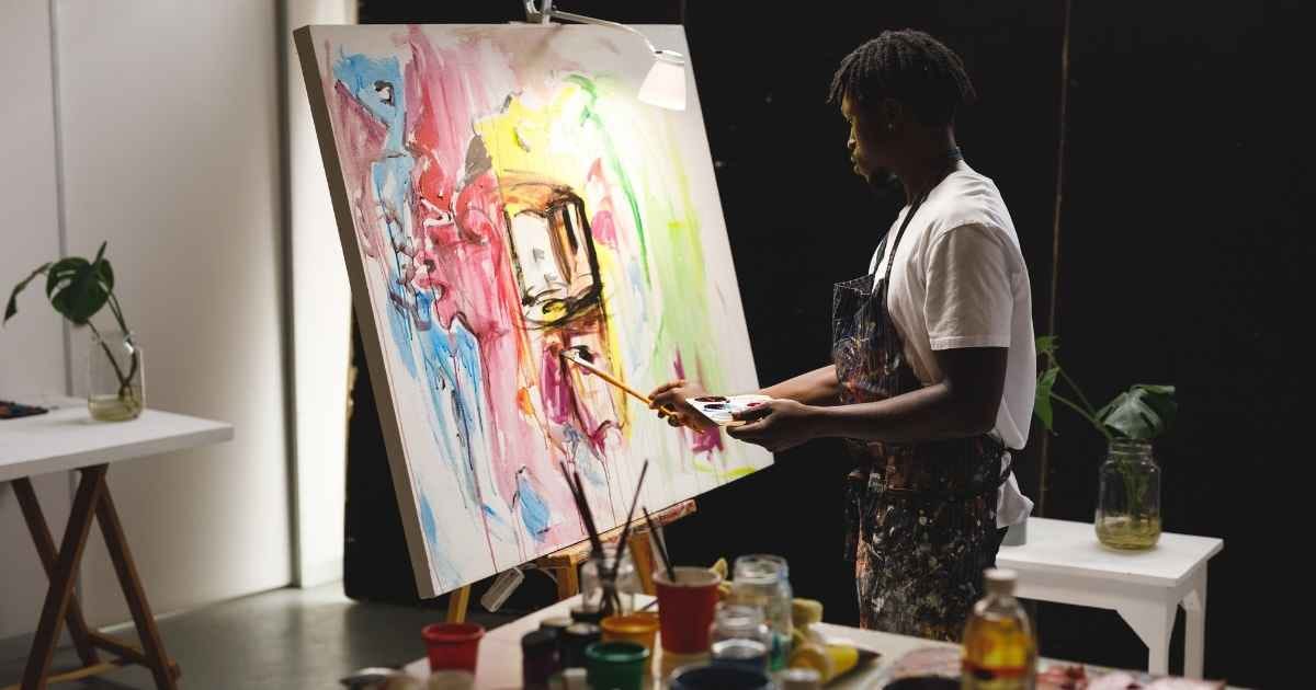 Painter at work painting on canvas in art studio Painter at work painting on canvas in art studio