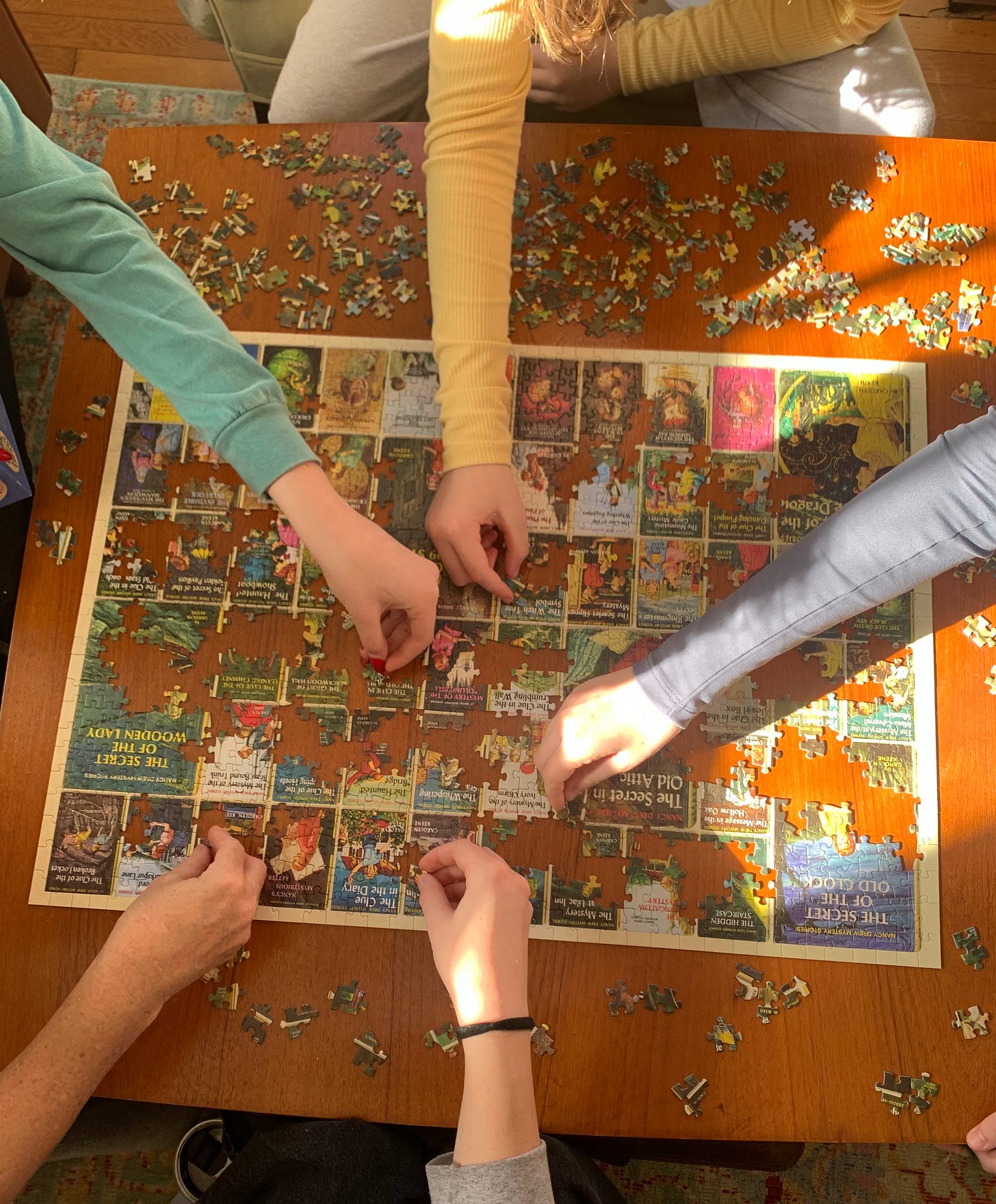 five arms each with fingers grasping puzzle pieces all hovering over a puzzle