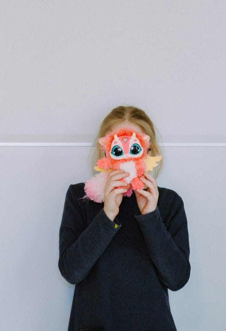 a little girl holding a stuffed animal in front of her face