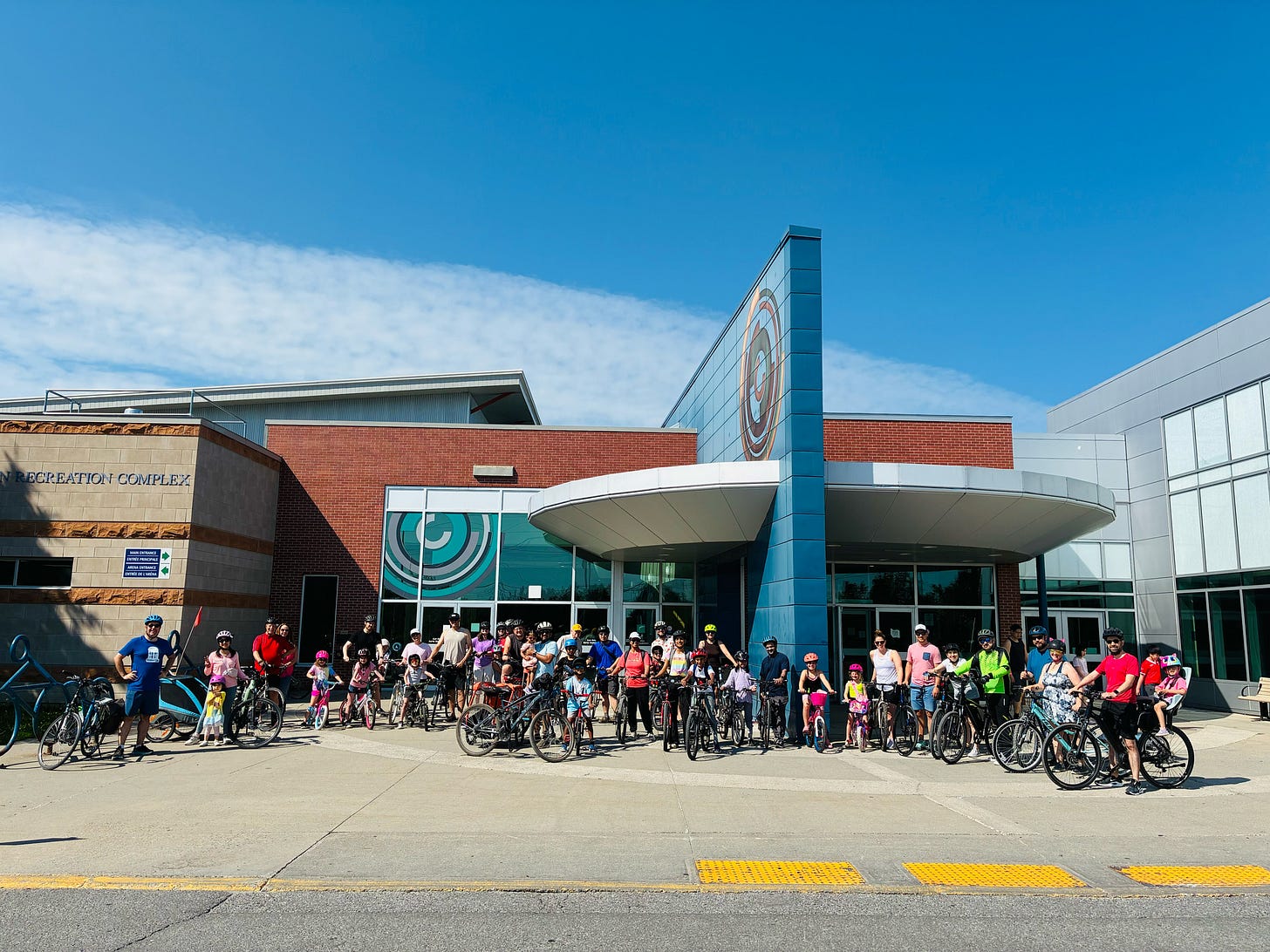 A large group of people with bikes standing in front of CARDELREC in Stittsville on a sunny day.