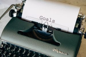 old typewriter with a piece of paper in it with "goals" typed on the paper 