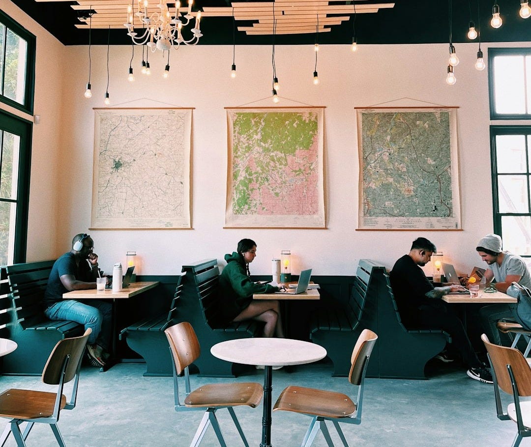 a group of people sitting at tables in a restaurant a group of people sitting at tables in a restaurant