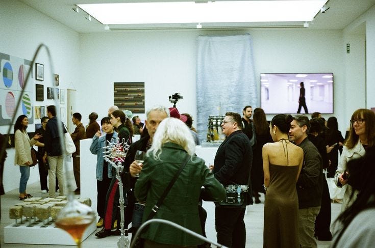 This may contain: a group of people standing in a room with art on the walls and pictures on the wall
