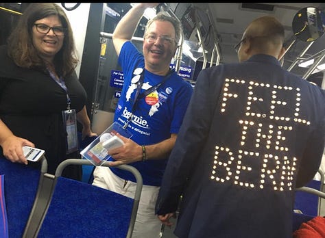 Kacey Carpenter holding signs, wearing shirts, buttons, and voting for Bernie Sanders as DNC delegate in Philly in 2016