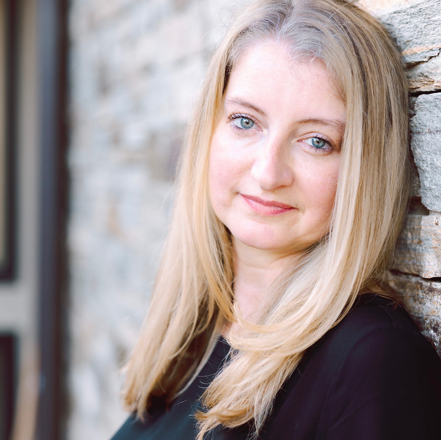 white woman with long blond hair and blue eyes in black shirt