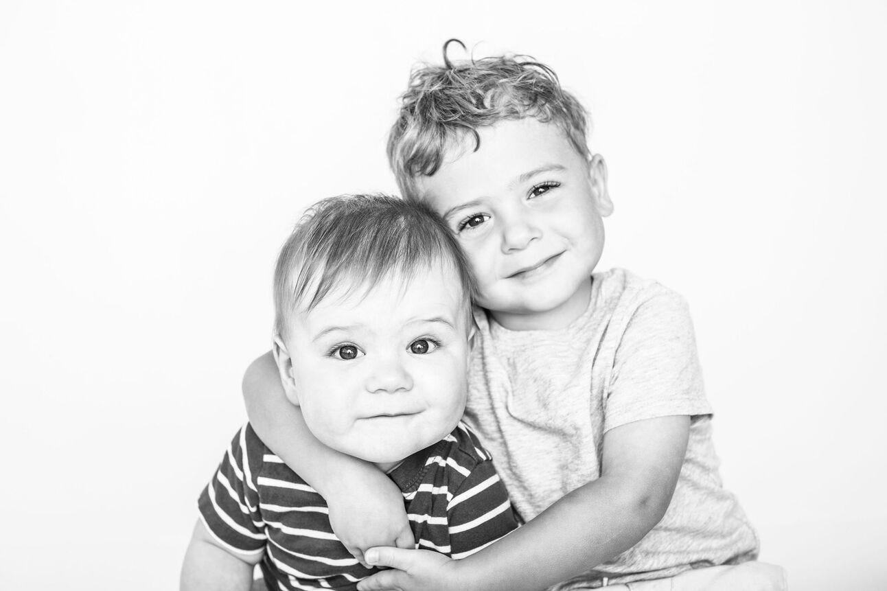 Two brothers hugging and smiling at the camera
