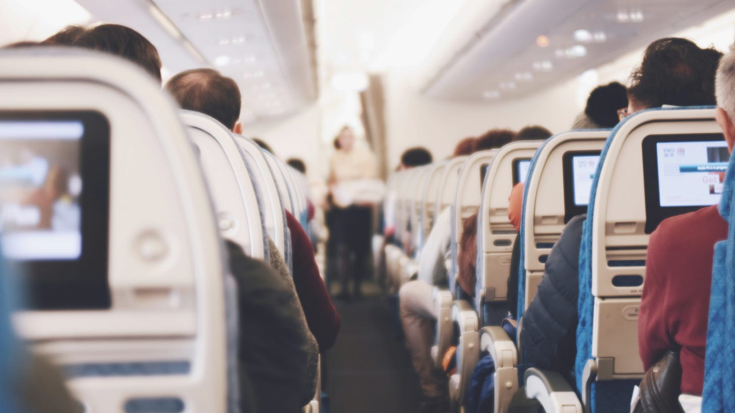 view down the aisle of an airplane full of seated passengers view down the aisle of an airplane full of seated passengers