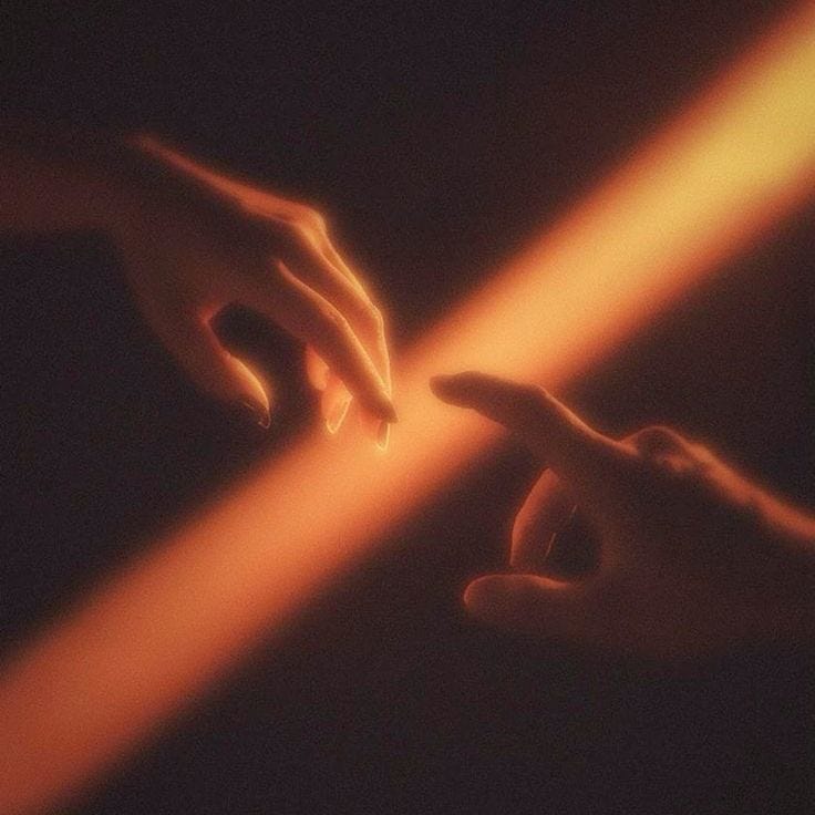 This may contain: two hands reaching towards each other with light coming from them in the dark night sky