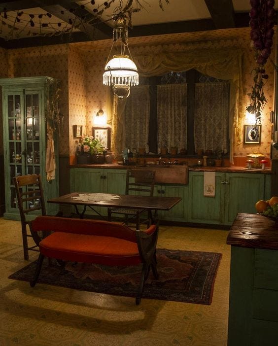 A dimly-lit kitchen interior with orange bench seat, dark wooden table and two kitchen chairs, a worn rug underneath, and surrounded by dull green cupboards with a wooden bench on top A dimly-lit kitchen interior with orange bench seat, dark wooden table and two kitchen chairs, a worn rug underneath, and surrounded by dull green cupboards with a wooden bench on top